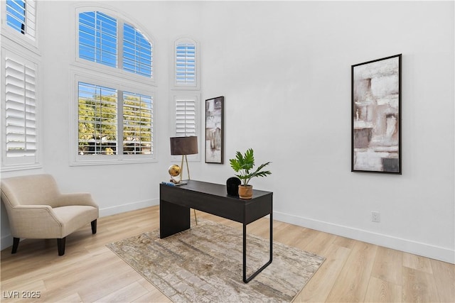 office with light hardwood / wood-style flooring and a high ceiling