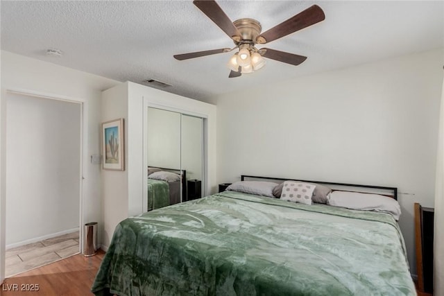 bedroom featuring a textured ceiling, a closet, ceiling fan, and light wood-type flooring