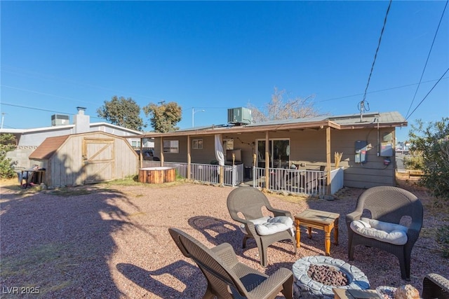 rear view of house featuring cooling unit, a shed, and an outdoor fire pit