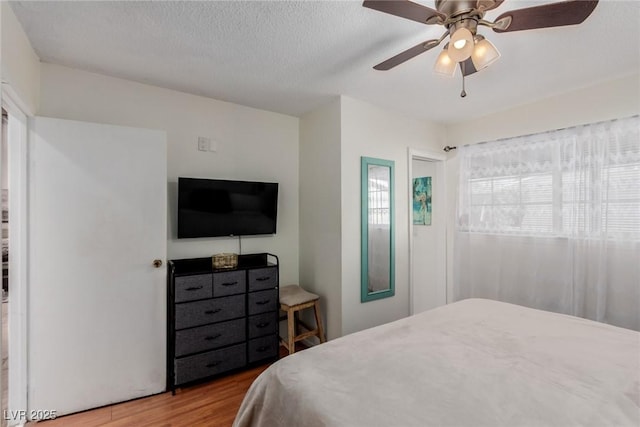 bedroom with hardwood / wood-style flooring, a textured ceiling, and ceiling fan