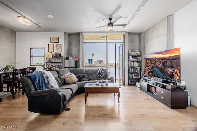 living room featuring floor to ceiling windows, ceiling fan, and light hardwood / wood-style flooring