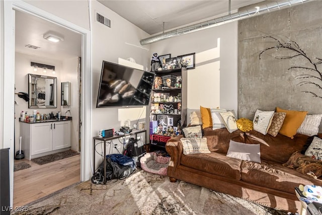 living area with visible vents and wood finished floors