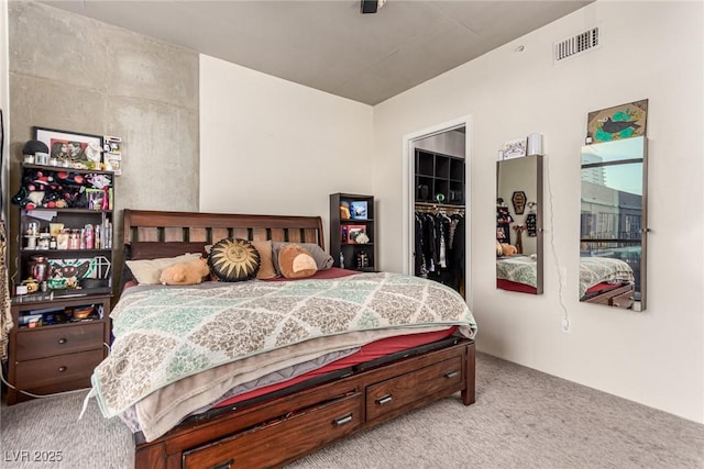 carpeted bedroom with a closet, a walk in closet, and visible vents