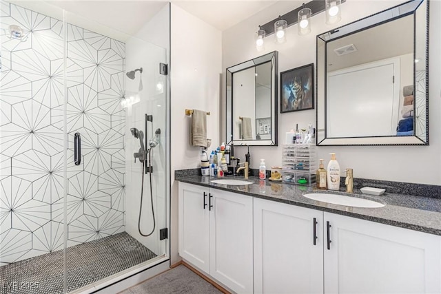 bathroom featuring visible vents, a sink, a shower stall, and double vanity