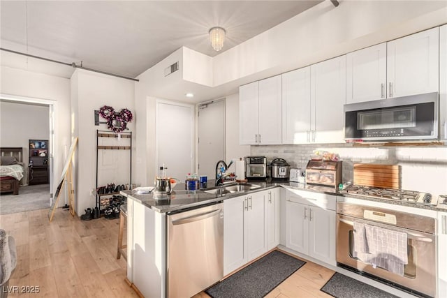 kitchen featuring appliances with stainless steel finishes, a sink, visible vents, and white cabinetry