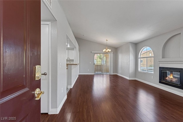 unfurnished living room with a fireplace, hardwood / wood-style floors, lofted ceiling, and a notable chandelier