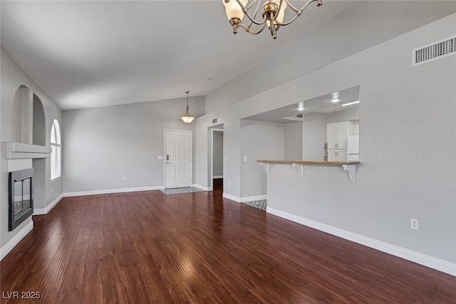 unfurnished living room featuring dark wood-type flooring and an inviting chandelier