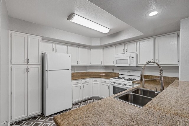 kitchen featuring a textured ceiling, kitchen peninsula, white cabinets, and white appliances