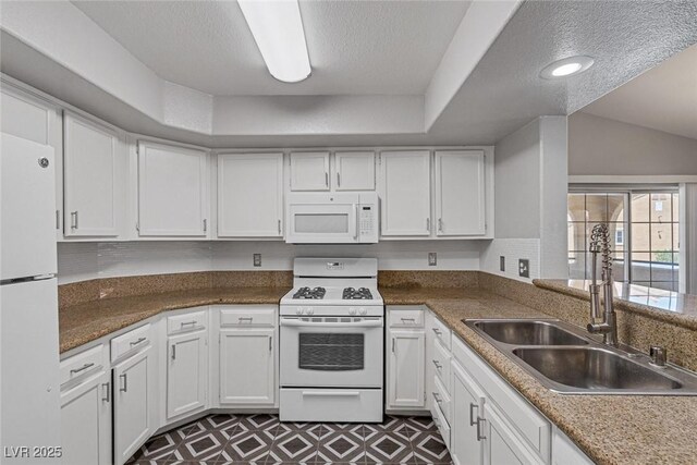 kitchen with sink, a textured ceiling, lofted ceiling, white appliances, and white cabinets