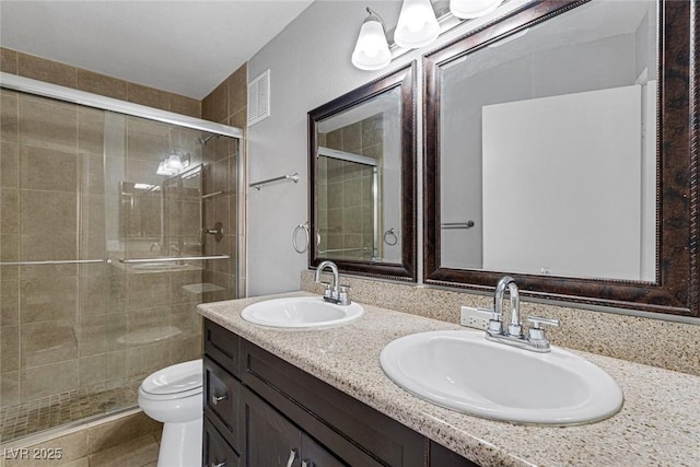 bathroom with a shower with door, vanity, and toilet