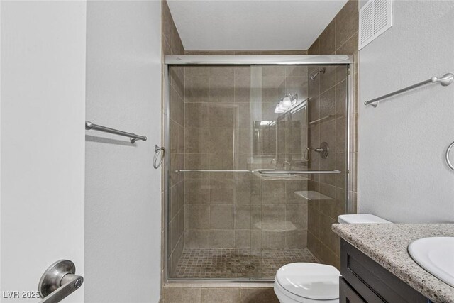 bathroom with vanity, toilet, and a shower with shower door