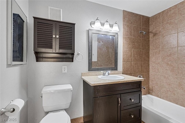 full bathroom with vanity, tiled shower / bath combo, and toilet