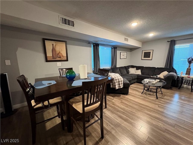 dining space featuring light hardwood / wood-style floors and a textured ceiling