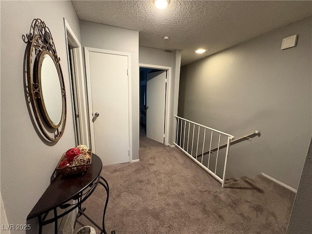 hallway with a textured ceiling and carpet