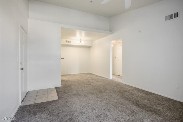 carpeted spare room featuring visible vents, baseboards, and ceiling fan