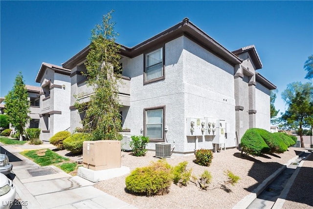 exterior space with stucco siding and cooling unit