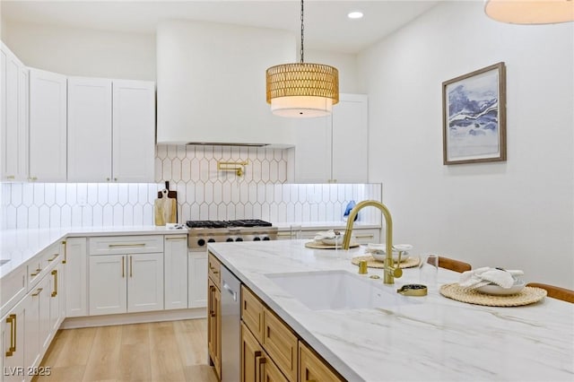 kitchen with white cabinetry, sink, light stone countertops, tasteful backsplash, and pendant lighting