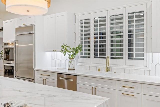 kitchen with light stone counters, sink, white cabinets, and appliances with stainless steel finishes