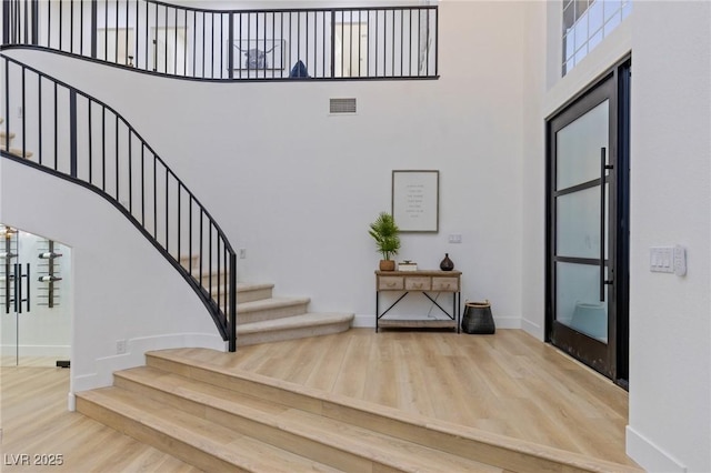 foyer entrance featuring wood-type flooring and a towering ceiling