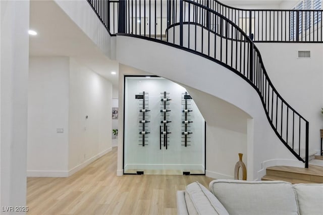 stairs with wood-type flooring and a high ceiling