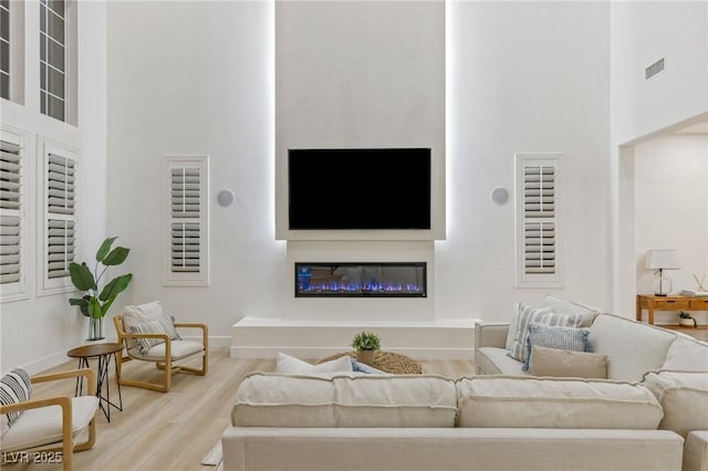 living room featuring a high ceiling and light hardwood / wood-style floors