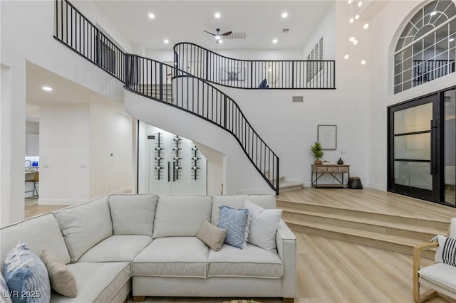 living room featuring ceiling fan, a towering ceiling, and wood-type flooring