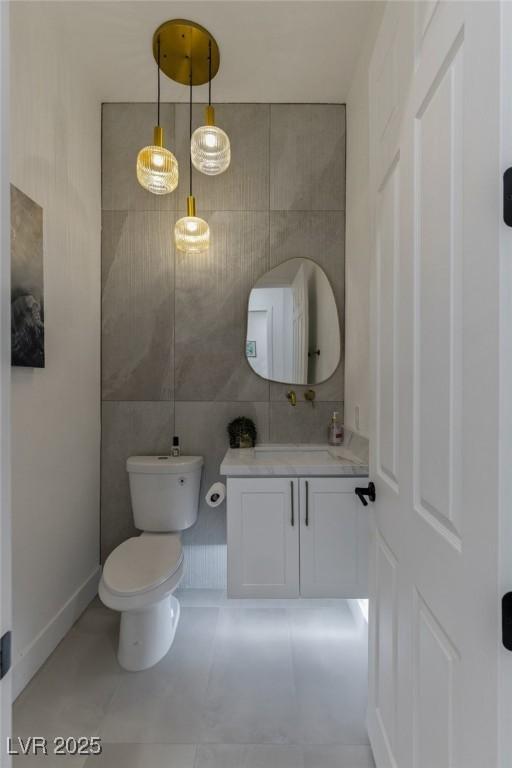 bathroom featuring vanity, toilet, and tile walls