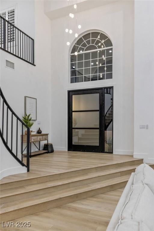 entrance foyer with hardwood / wood-style flooring, a high ceiling, and an inviting chandelier