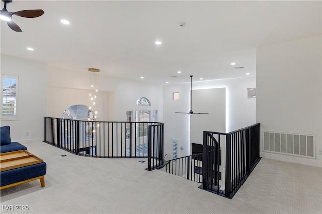 hallway featuring light carpet and a notable chandelier