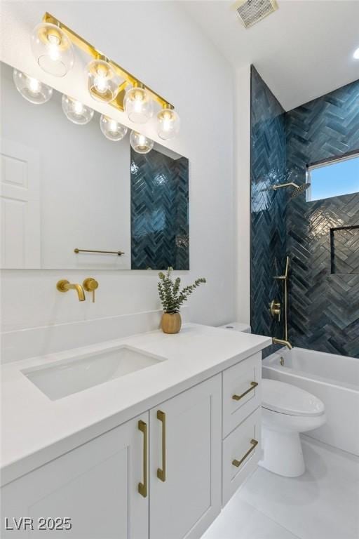 full bathroom featuring tile patterned floors, tiled shower / bath, vanity, and toilet