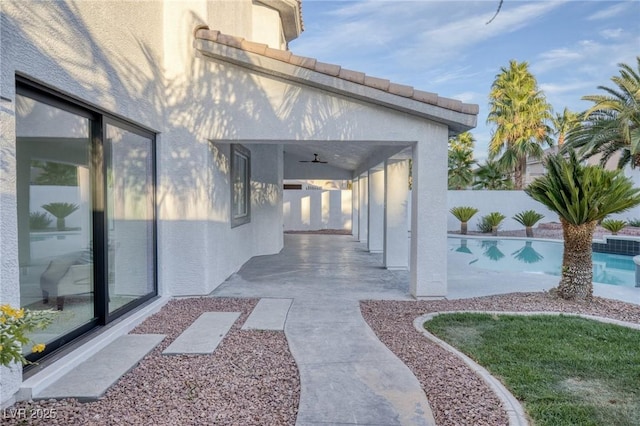 property entrance with a fenced in pool, ceiling fan, and a patio area