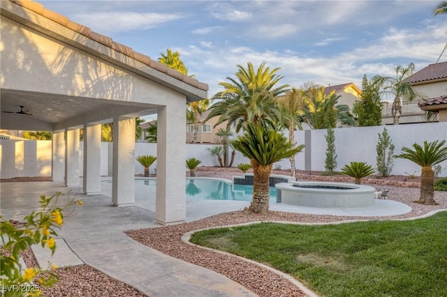 exterior space featuring an in ground hot tub, a patio, ceiling fan, and a lawn