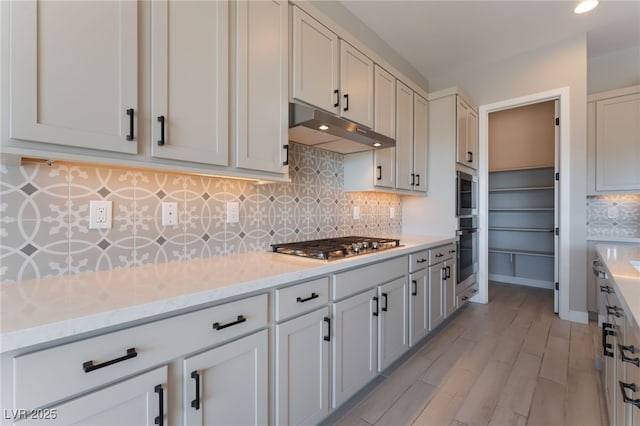 kitchen featuring white cabinetry, light stone counters, and light wood-type flooring