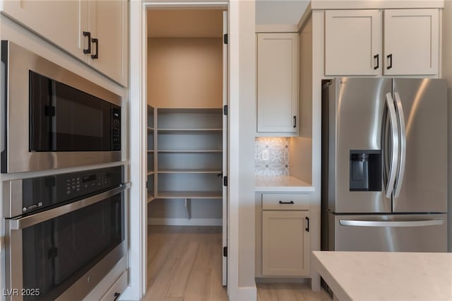 kitchen featuring appliances with stainless steel finishes, backsplash, and light hardwood / wood-style floors