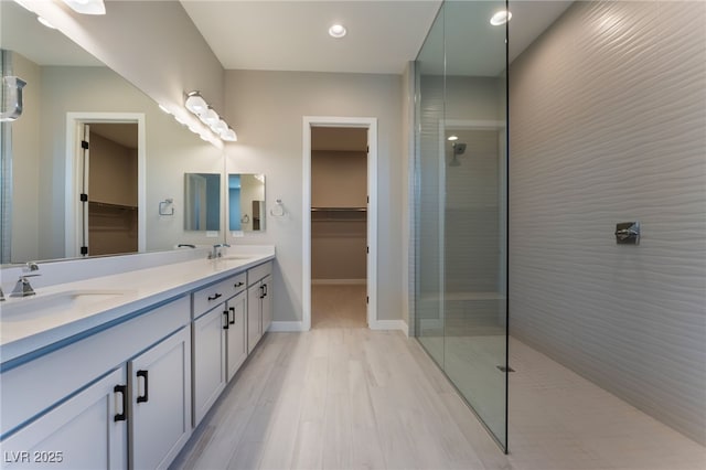 bathroom featuring a tile shower, vanity, and wood-type flooring