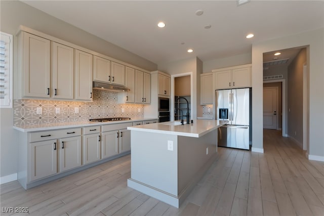 kitchen with a center island with sink, white cabinets, light wood-type flooring, and appliances with stainless steel finishes