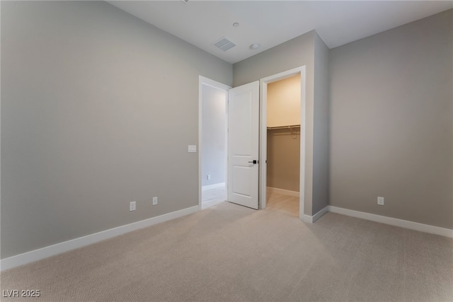 unfurnished bedroom featuring light colored carpet, a spacious closet, and a closet