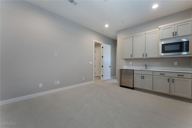 kitchen with stainless steel microwave, refrigerator, light colored carpet, and sink