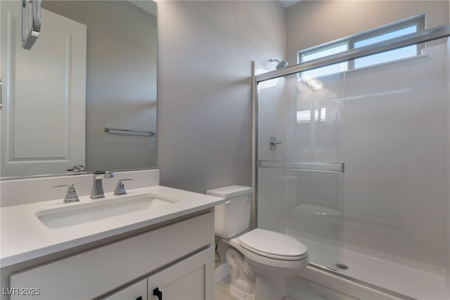 bathroom with vanity, toilet, and a shower with door