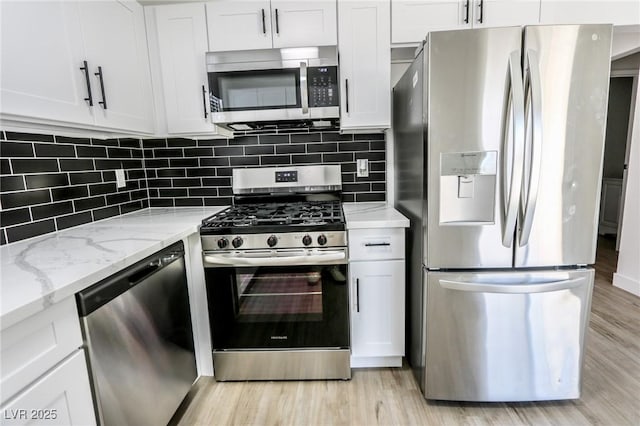 kitchen featuring decorative backsplash, appliances with stainless steel finishes, white cabinets, and light stone counters