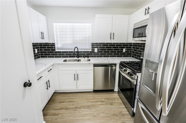 kitchen with sink, tasteful backsplash, light stone counters, white cabinets, and appliances with stainless steel finishes