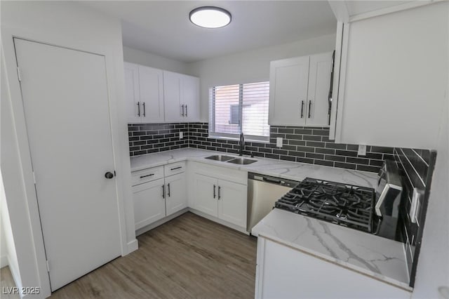 kitchen featuring light stone countertops, dishwasher, sink, tasteful backsplash, and white cabinets