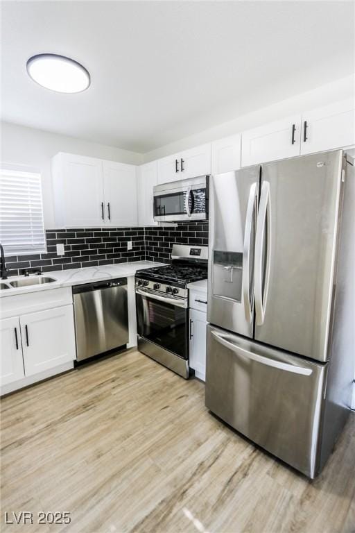 kitchen with white cabinetry, sink, tasteful backsplash, appliances with stainless steel finishes, and light wood-type flooring