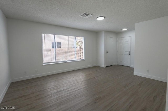 spare room featuring a textured ceiling and dark hardwood / wood-style floors