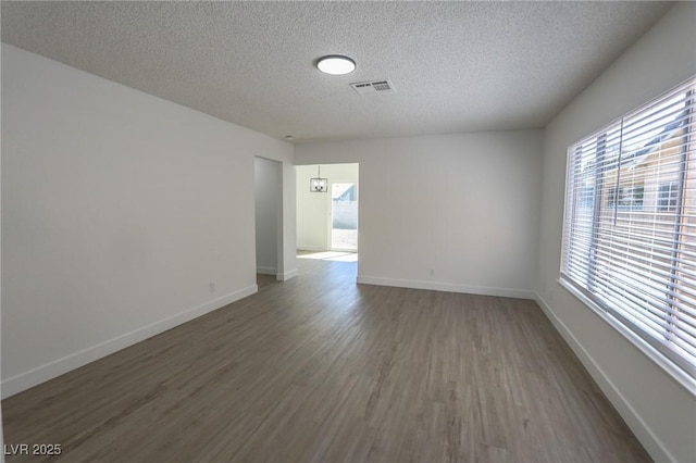 spare room featuring a textured ceiling and dark hardwood / wood-style flooring