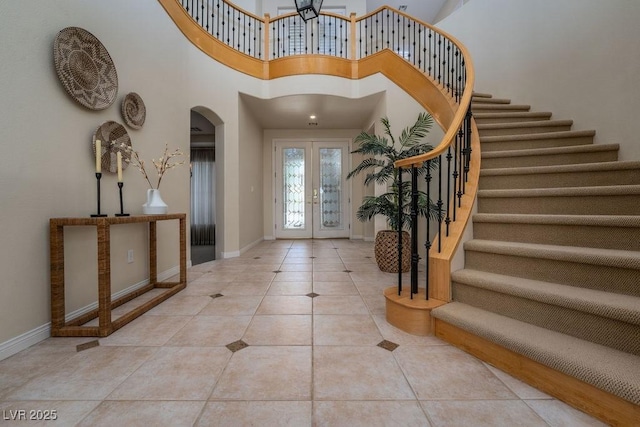 entryway featuring light tile patterned flooring, a high ceiling, and french doors