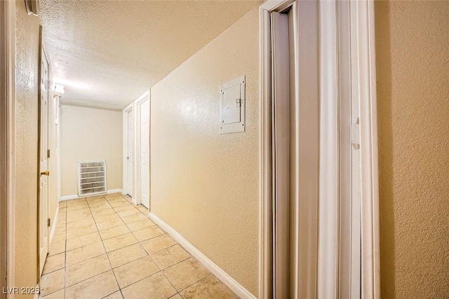 hallway with a textured ceiling, light tile patterned floors, and electric panel