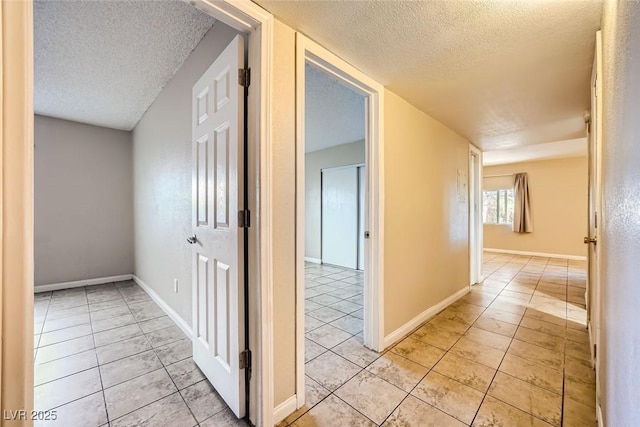 corridor featuring a textured ceiling and light tile patterned floors