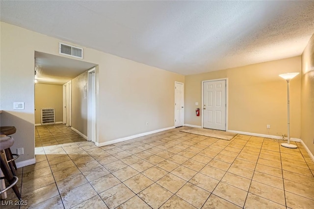 spare room with a textured ceiling and light tile patterned floors