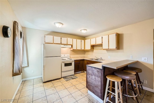 kitchen featuring kitchen peninsula, a kitchen bar, sink, white appliances, and light tile patterned floors